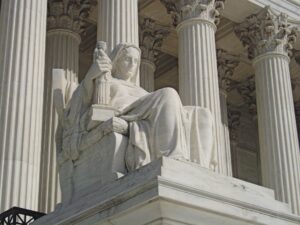 Photo of the statue of a woman sitting on a throne in front of the US Supreme Court
