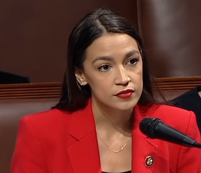 Alexandria Ocasio-Cortez stands in front of a microphone