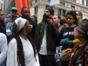 A group of people of color at Occupy in New York, Sonny Singh is in the center making an announcement.