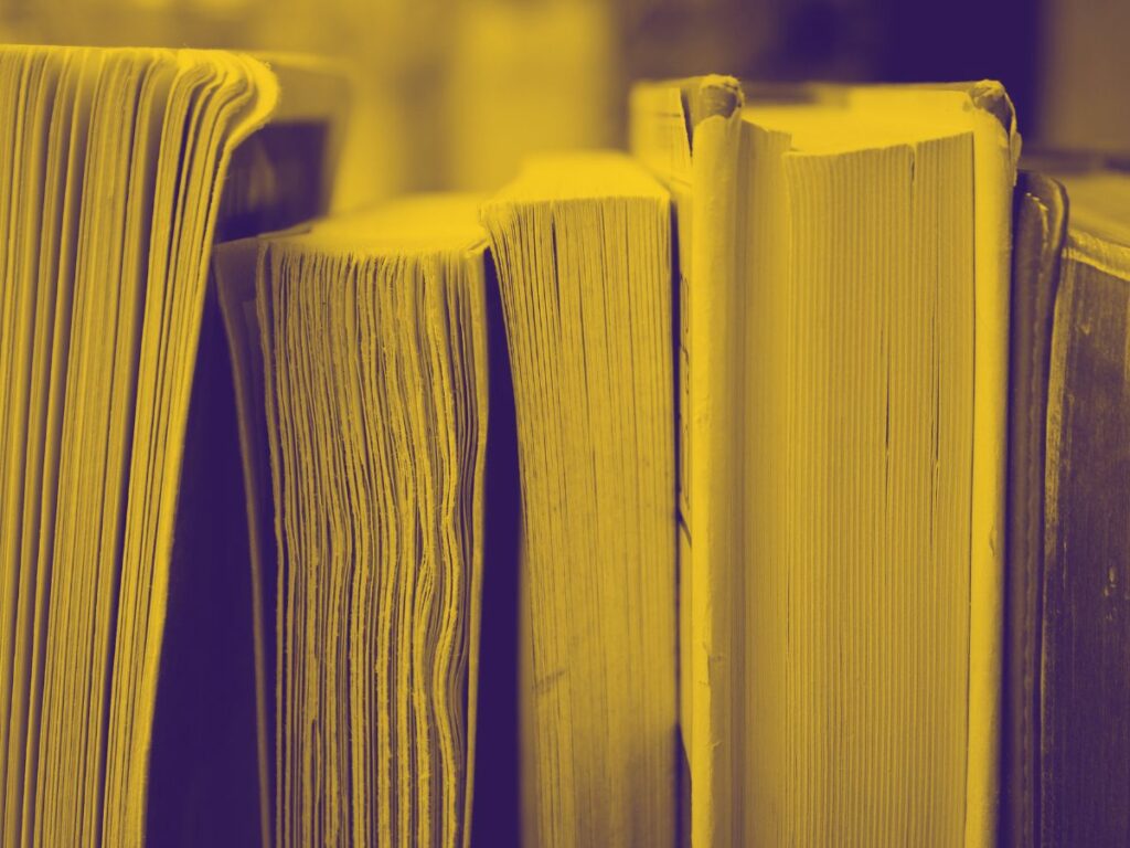 Yellow tinted photo of various books stacked next to each other